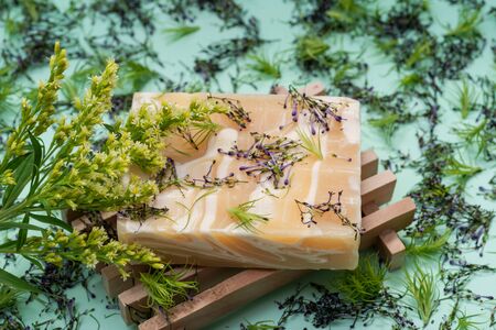 Wooden Soap Holder with Handmade ultra-moisturizing Almond Scented Goats Milk Bar Soap decorated with flower sprinkles confetti on green background.の写真素材