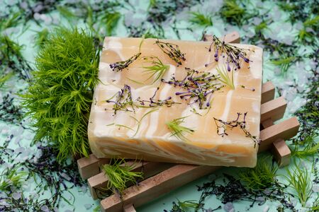 Wooden Soap Holder with Handmade ultra-moisturizing Almond Scented Goats Milk Bar Soap decorated with flower sprinkles confetti on green background.の写真素材