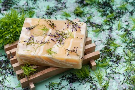 Wooden Soap Holder with Handmade ultra-moisturizing Almond Scented Goats Milk Bar Soap decorated with flower sprinkles confetti on green background.の写真素材