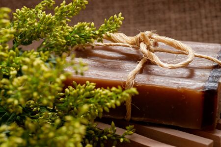 Fresh Aster Solidago Flowers, Wooden Soap Holder and handmade Frankincense & Myrrh Goat's Milk Bar Soap tied with jute rope on burlap background.の写真素材
