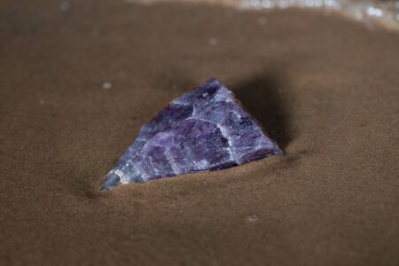 High grade rough natural Purple Auralite 23 Amethyst point from Canada on wet sand  in front of the lake at sunrise.の写真素材