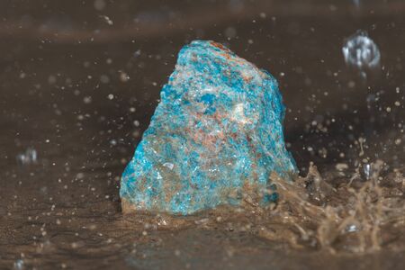 High grade rough natural Blue Apatite Specimen from Madagascar on wet sand  in front of the lake at...