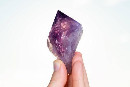 Woman holding Large Amethyst Phantom  Point from Brazil in her hand at sunrise in front of the lake.の写真素材