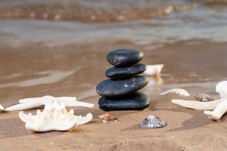 Spa composition - stacked Basalt Stones, Seashells and Sea Stars on the beach at sunrise in front of the ocean. Wellness, Balance and Relax concept.の写真素材