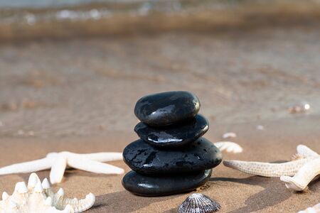 Spa composition - stacked Basalt Stones, Seashells and Sea Stars on the beach at sunrise in front of the ocean. Wellness, Balance and Relax concept.の写真素材