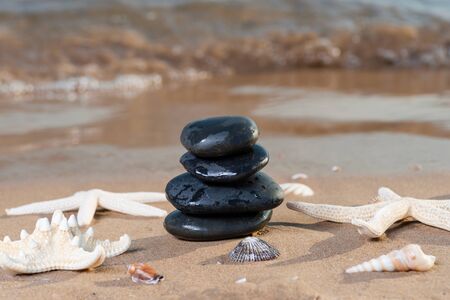 Spa composition - stacked Basalt Stones, Seashells and Sea Stars on the beach at sunrise in front of the ocean. Wellness, Balance and Relax concept.の写真素材