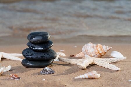 Spa composition - stacked Basalt Stones, Seashells and Sea Stars on the beach at sunrise in front of the ocean. Wellness, Balance and Relax concept.の写真素材