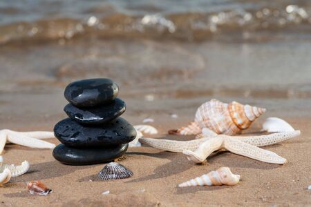 Spa composition - stacked Basalt Stones, Seashells and Sea Stars on the beach at sunrise in front of the ocean. Wellness, Balance and Relax concept.の写真素材