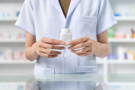 Close up of female pharmacist hand holding pill bottle showing to camera, She wearing lab coat...