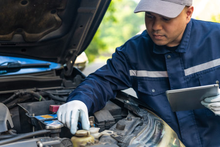 Asian automobile mechanic repairman wearing uniform and protection glove repairing a car engine...