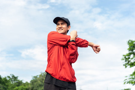 Medium shot, Young Asian man stretching his body warm up before workout outdoor with sky background....