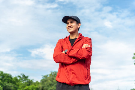 Portrait of a smiling young adult asian man wearing sportswear in running track. Happy handsome male...