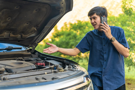 Asian man having trouble with his broken car on the highway roadside and use a cellphone call garage...
