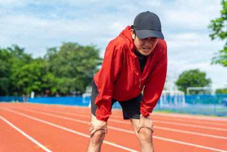 Asian runner man tired during jogging in the running track. Young asian male intense training...