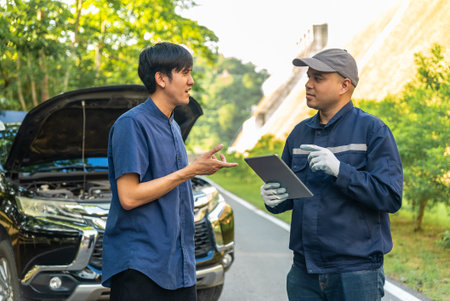 Handsome asian mechanic man shows the car report on a digital tablet to asian client at the...