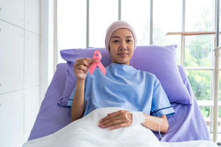 Asian woman breast cancer patient placing pink ribbon on hand as symbol of breast cancer awareness....