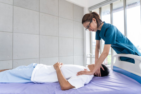 Young asian man patient undergoes chiropractic physical therapy under the supervision of a smiling...