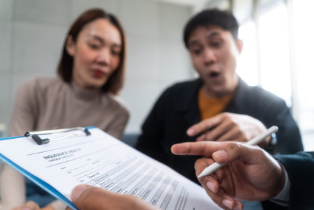 Happy asian couple is planning to sign up for a joint insurance plan covering health, life and...