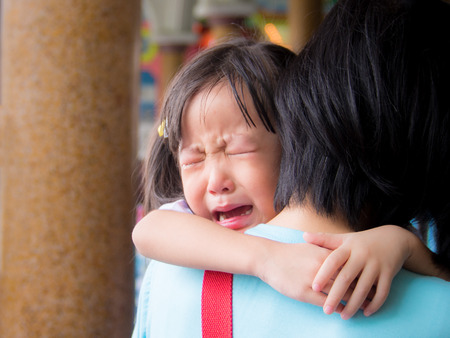 Asian baby girl hugging her mother cryingの写真素材