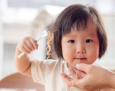 Happy Asian child eating delicious noodle