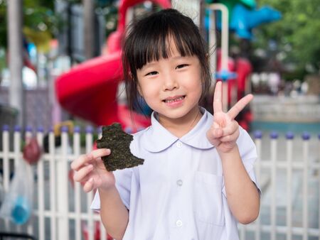 Happy Asian child eating delicious nori seaweedの写真素材
