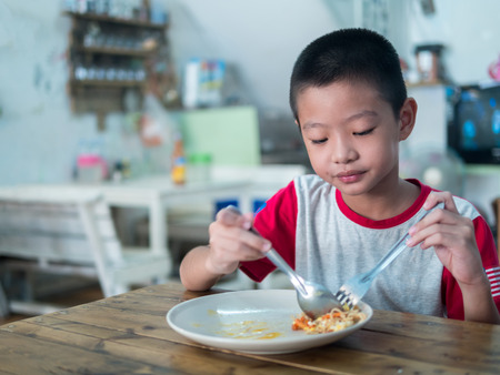 Happy Asian boy eating delicious noodleの写真素材
