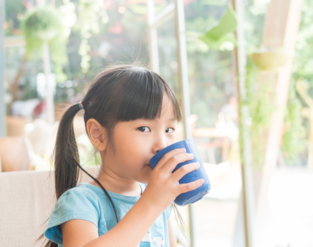 Asian girl child drink some water from the blue glassの写真素材