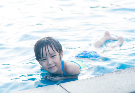Asian girl is playing in the pool, laying downの写真素材