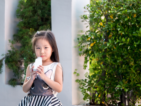 portrait of Asian adorable little girl hold bottle of milkの写真素材
