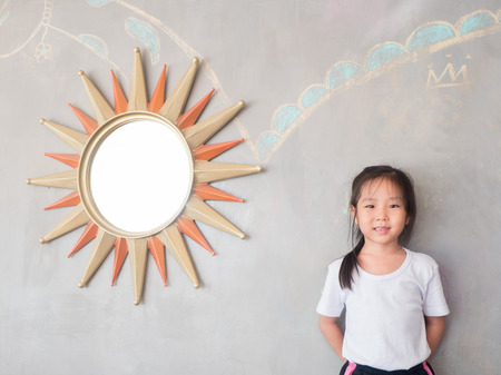 portrait of Asian adorable little girl with the mirror, sun symbolの写真素材