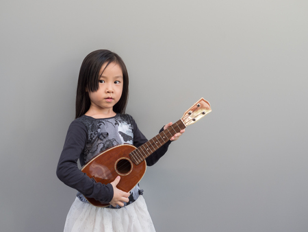 Little asian child play the melodion, gray backgroundの写真素材