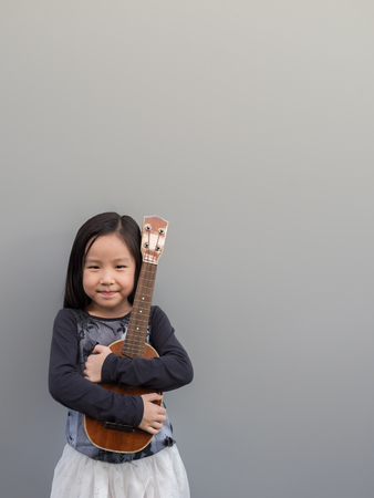 Little asian child play the melodion, gray backgroundの写真素材