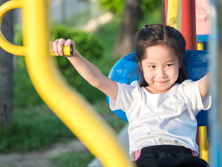 Happy asian baby child playing on playground , exercise equipment in the gardenの写真素材