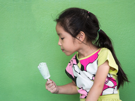 Little Asian girl eating ice cream, in summerの写真素材
