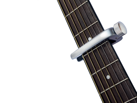 capo on guitar fingerboard, white background , close up
