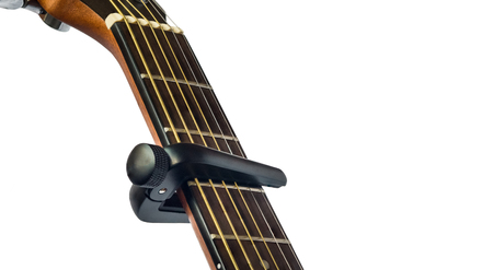 capo on guitar fingerboard, white background , close up