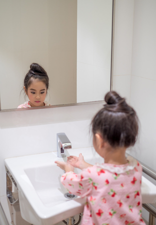 Asian little kid girl wash her hand in the toiletの写真素材