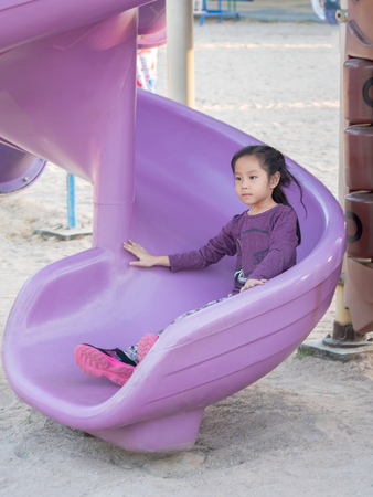 Happy kid, asian baby child girl playing on playground, sliderの写真素材