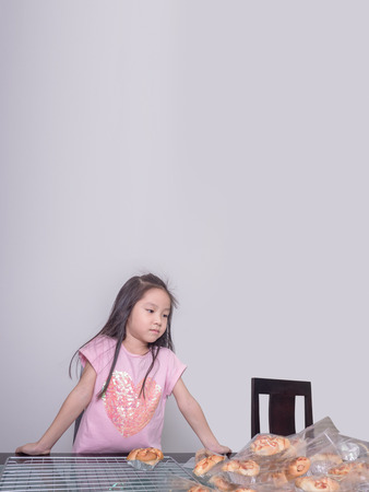 Adorable  kid girl separate packing baked pork sausage with mayonnaise bread,  domestic kitchen, Child  helping his parentsの写真素材