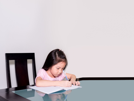 Asia little student girl studying and doing his homework  at home,  on the table, home educationの写真素材