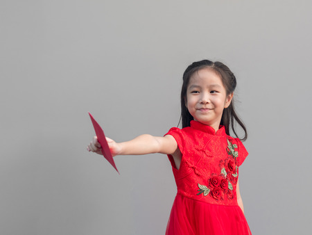 Cute Asian girl in chinese cheongsam and Tradition Chinese dress with red envelope , Chinese new year concept , grey backgroundの写真素材