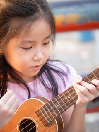 Little asian child girl play the ukulele, in the garden on the Steel pipe, practice to playの写真素材