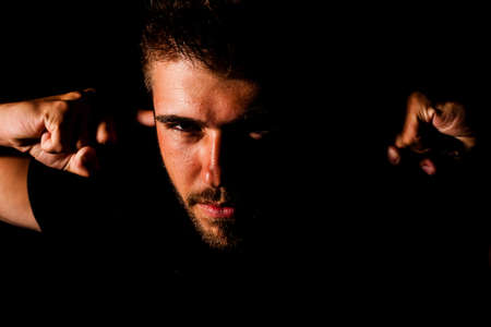 Portrait of a young man with three - day beard puts his fingers in his own ears.の写真素材