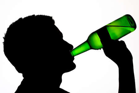 Male silhouette drinking beer lit from behindの写真素材