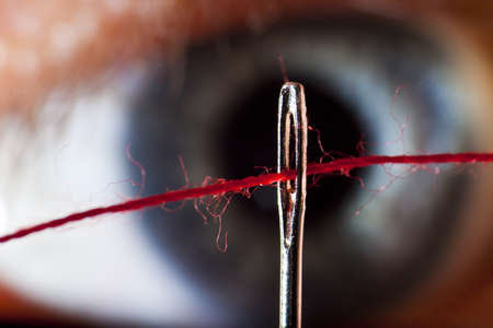 Close up of an eye looking at threaded needleの写真素材