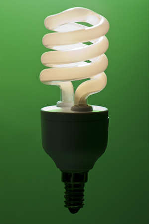 A lit low energy lightbulb against a green backgroundの写真素材