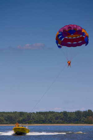 Lake Tisza, Hungary - August 20, 2010: Man Paragliding being pulled by yellow speedboat