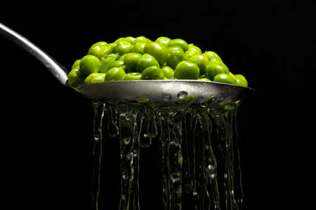 Garden peas being drained through a slotted spoonの写真素材