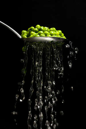 Garden peas being drained through a slotted spoonの写真素材