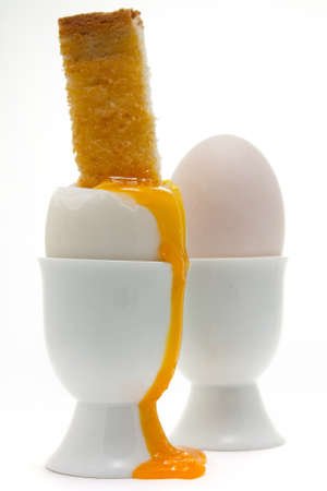 Boiled egg with a toasted soldier in an egg cup with a dripping vibrant egg yolk